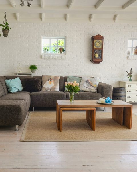 Landelijke woonkamer met een robuuste salontafel in massief hout, linnen gordijnen en aardetinten