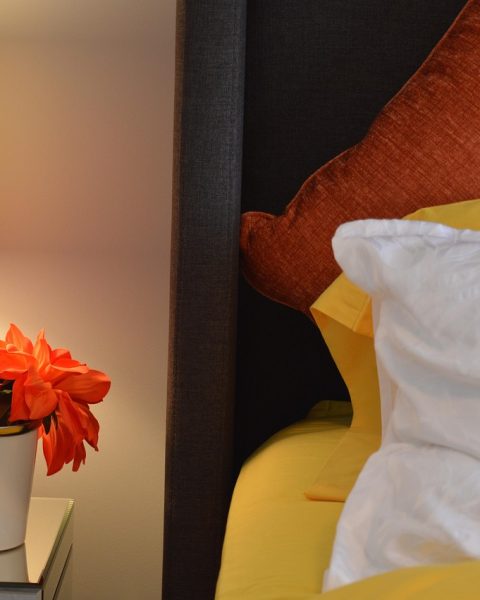 Stijlvolle nachtkastlamp op een marmeren voet naast een opgemaakt bed in een moderne slaapkamer