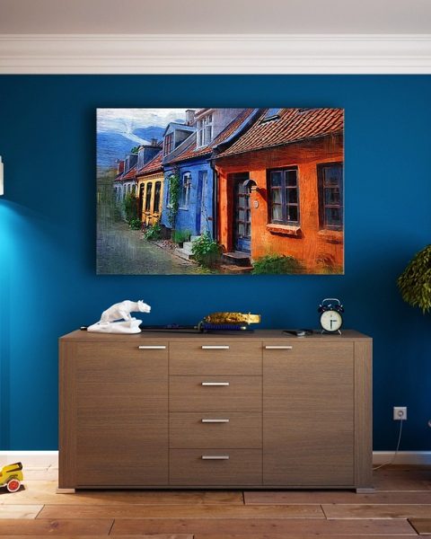 Een origineel schilderij hangend aan de muur boven een bank in een lichte woonkamer