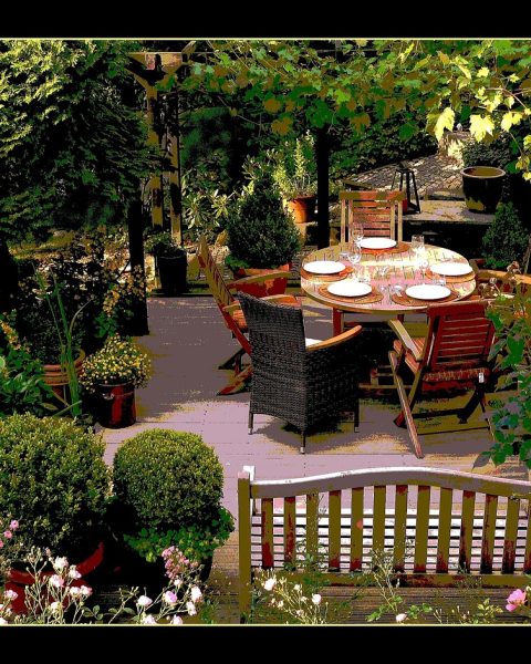 Chique gedekte tafel op een zomers terras met linnen loper, aardewerk en kaarsen in terracottahouders