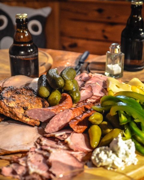 Een stijlvol opgemaakt charcuterie bord met dun gesneden vleeswaren, kaas en garneringen op een houten plank