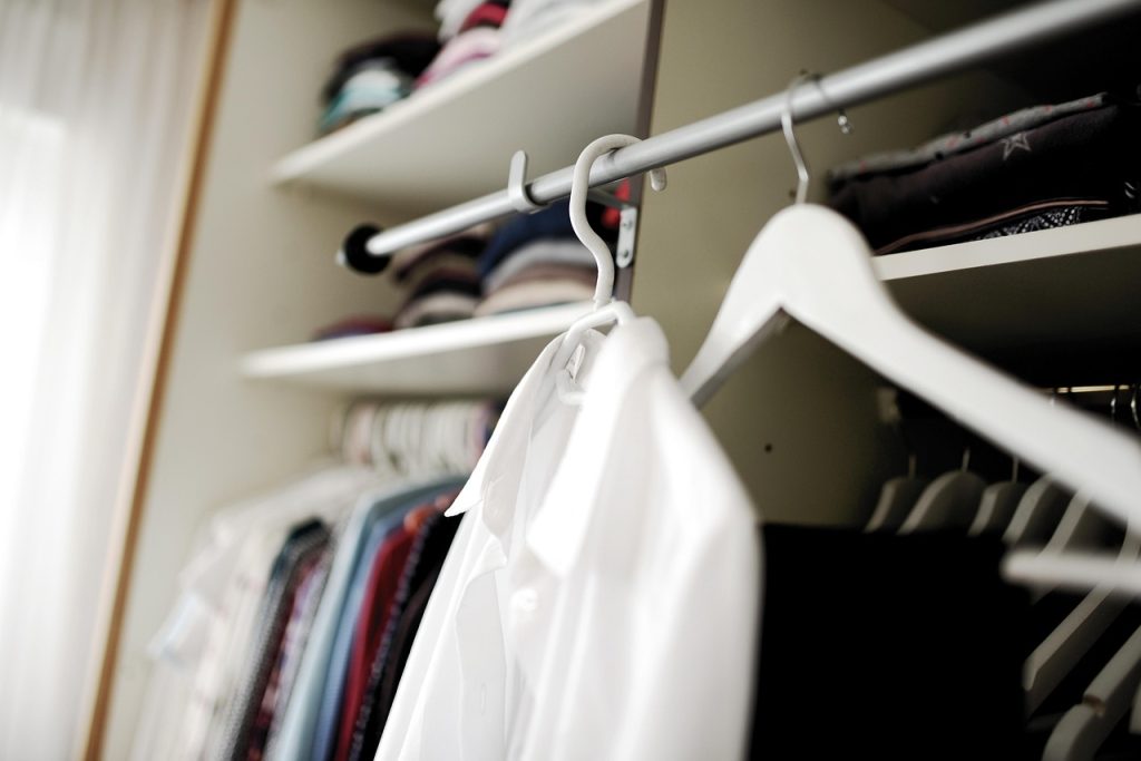 Netjes georganiseerde kleine kledingkast met fluwelen hangers en stapeldozen