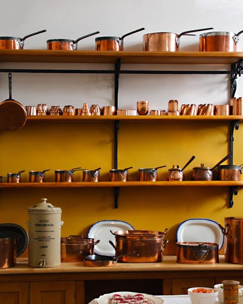 Koperen pannen met warme patina hangend in een moderne keuken met marmeren aanrecht