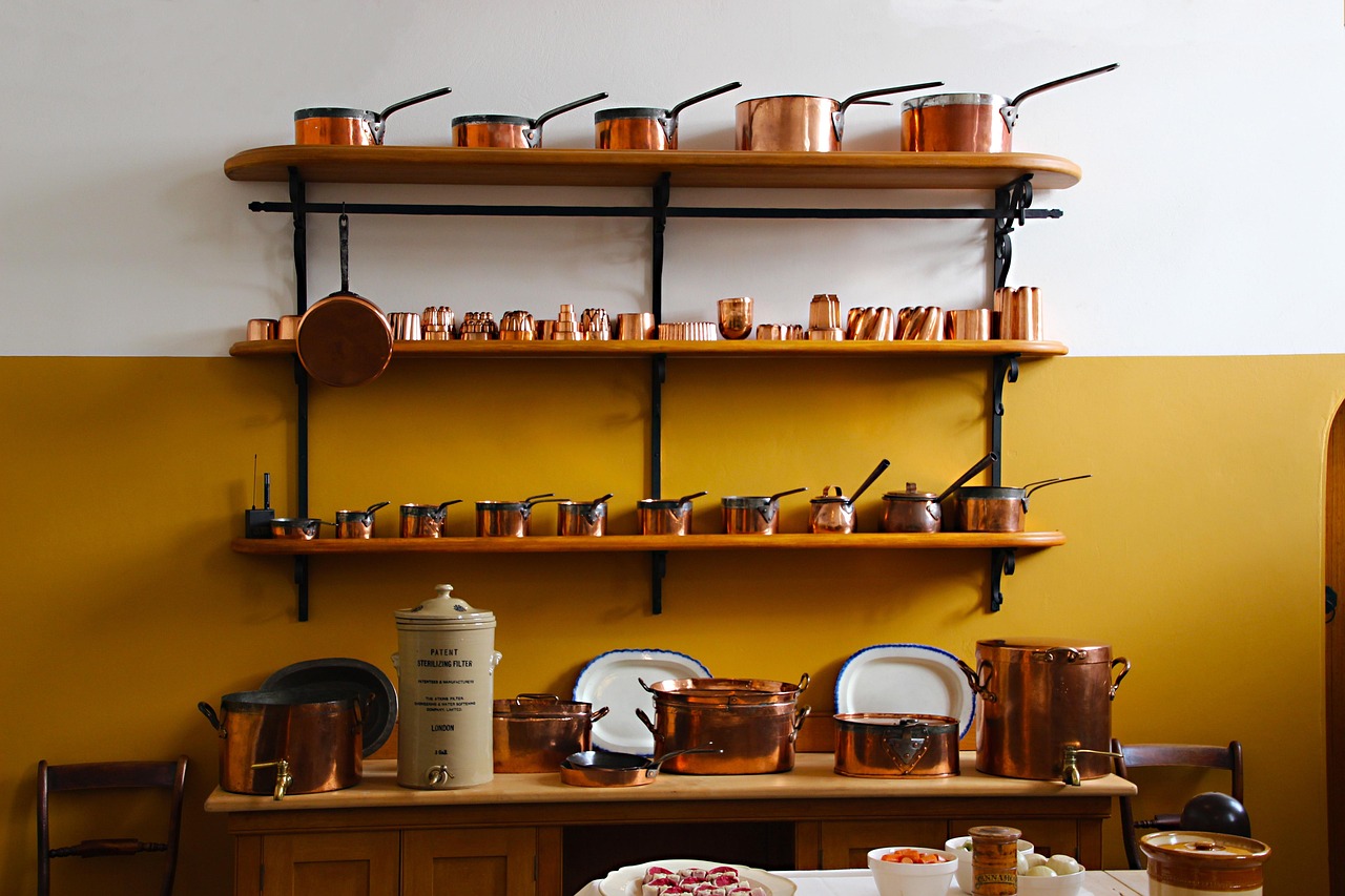 Koperen pannen met warme patina hangend in een moderne keuken met marmeren aanrecht